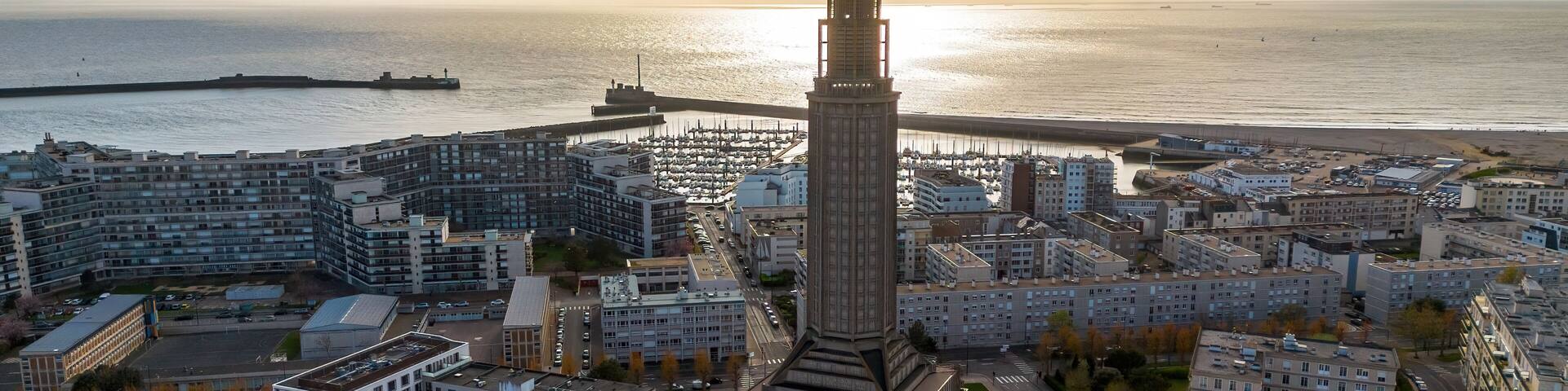 Backlit silhouette of St. Joseph Church tower over shimmering sea water in Le Havre, Normandy, France