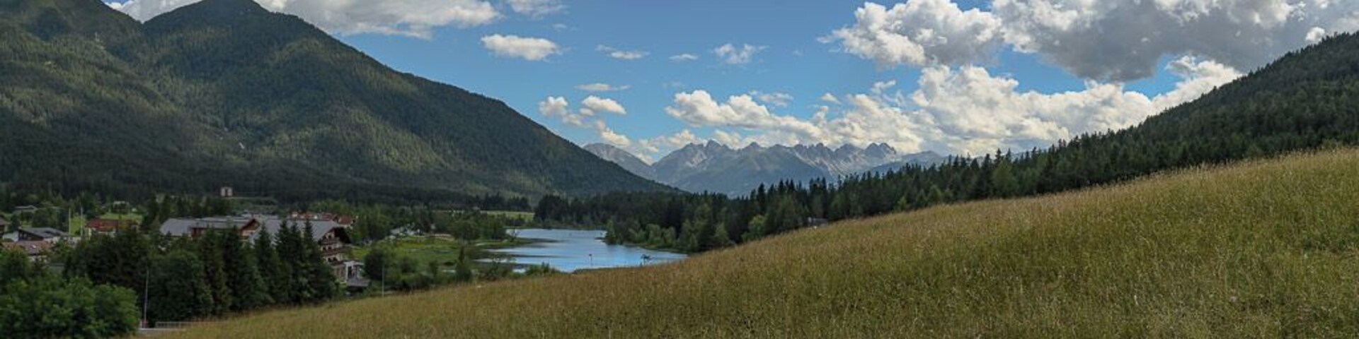 Un paisaje montañoso con un lago, un pueblo y cielo despejado.