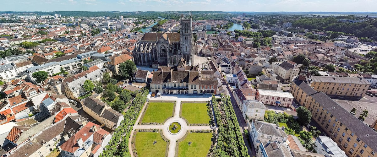 An aerial view of a historic city with a prominent cathedral, a river, and surrounding residential areas.