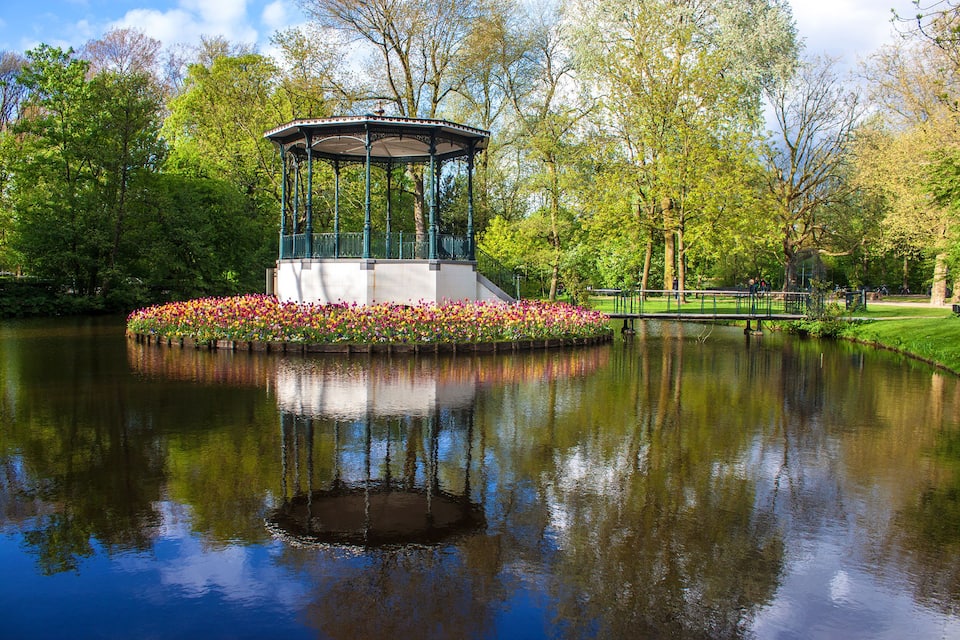 A gazebo surrounded by flowers and a pond.