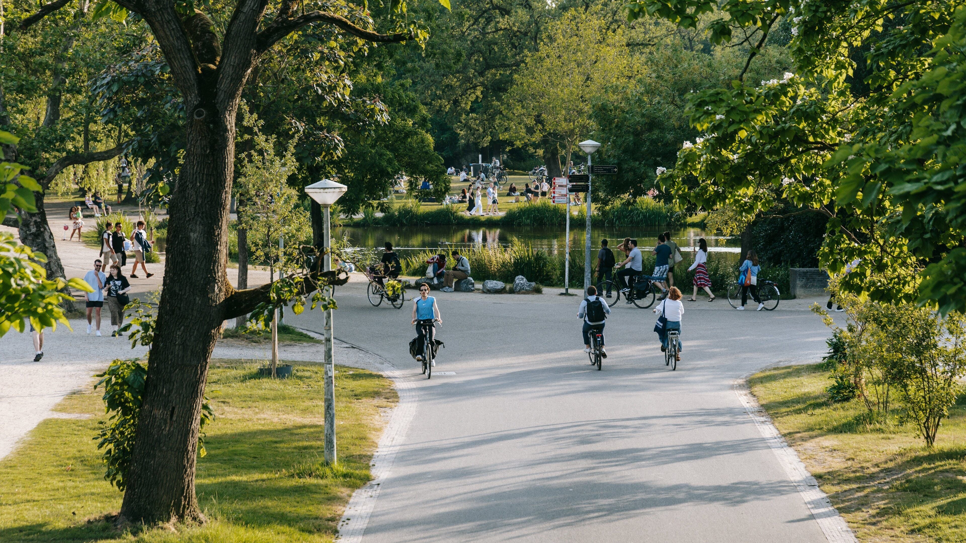 A park with a paved path, cyclists, and people walking.