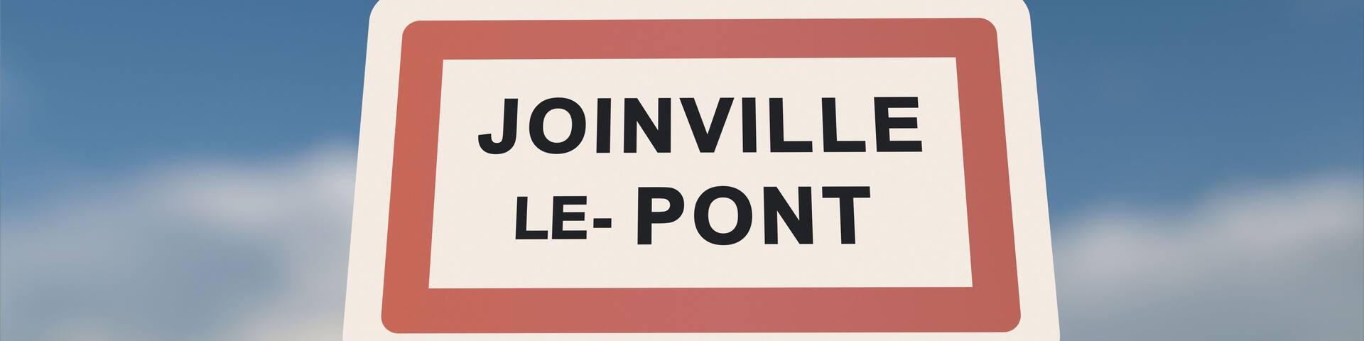 A sign with the text 'JOINVILLE LE-PONT' against a clear sky.