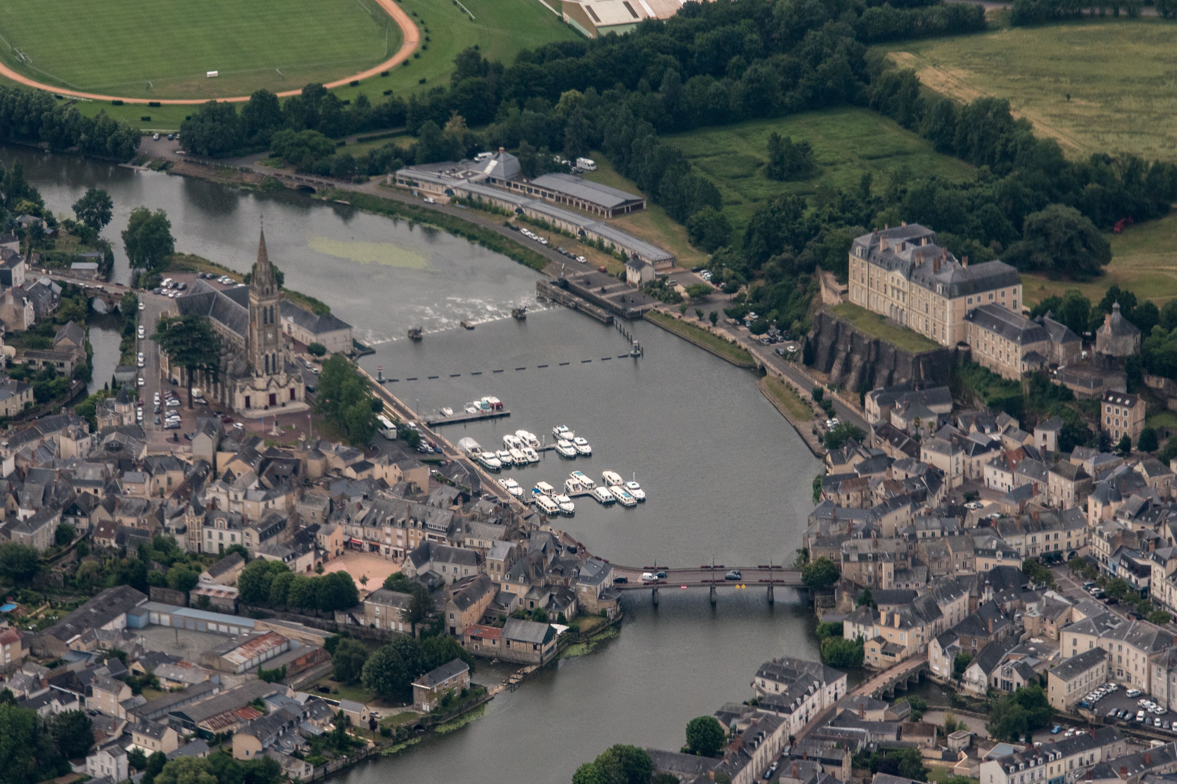 An aerial view of a historic town with a river, a church, and a castle.