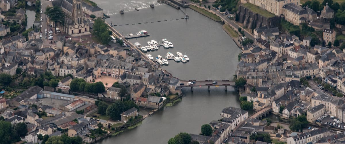 An aerial view of a historic town with a river, a church, and a castle.