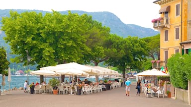 A lakeside outdoor dining area with tables and umbrellas, surrounded by trees and a mountain in the background.