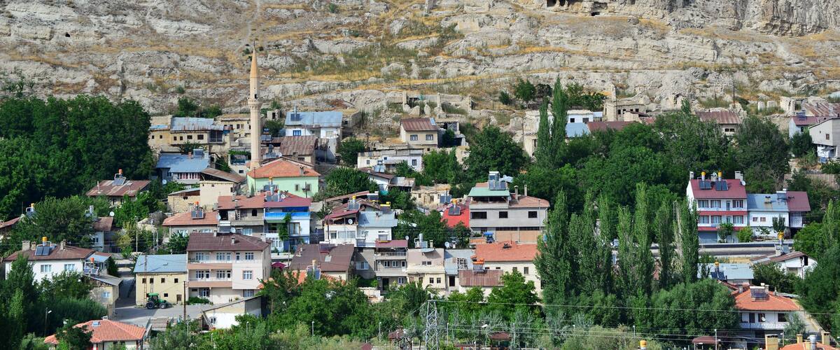 A town nestled against a rocky cliff with visible cave dwellings.