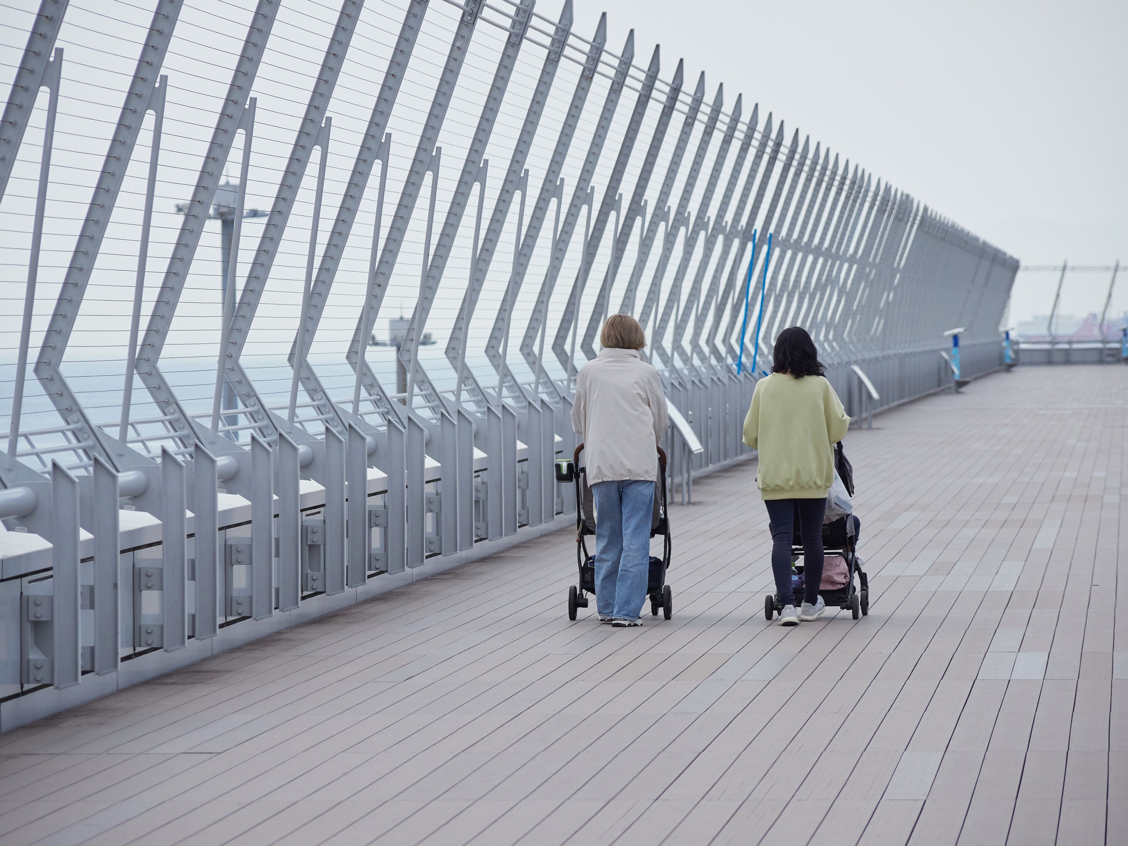 A pedestrian bridge with a metal railing and a view of the water below.