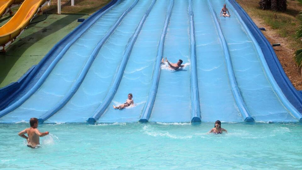 A water park with multiple water slides and people enjoying the slides.