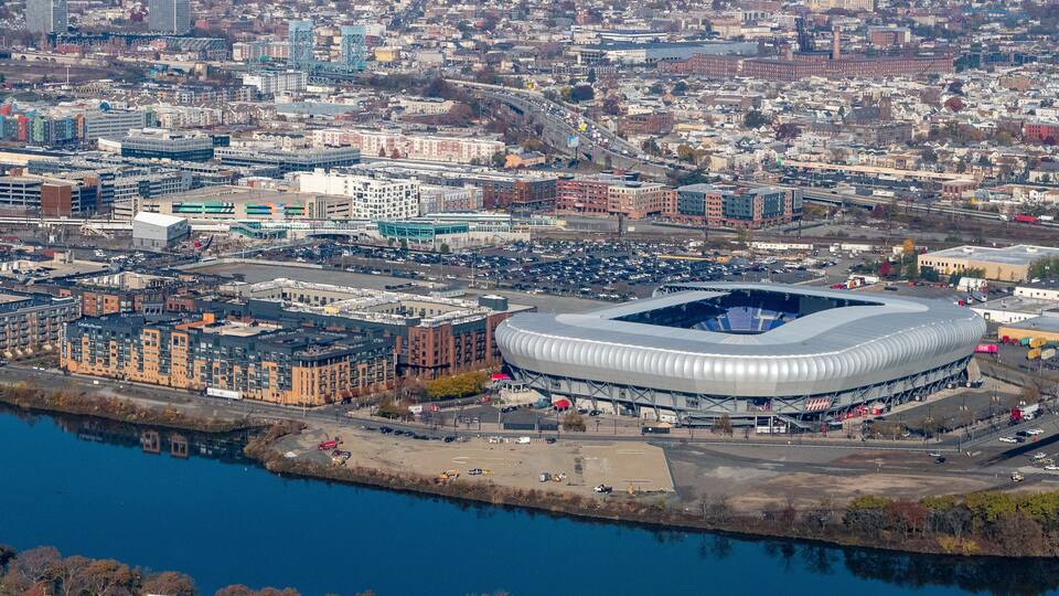 A large stadium surrounded by a cityscape with buildings and a river.