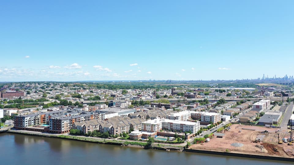 A river with buildings along the banks, a distant city skyline, and a construction site.