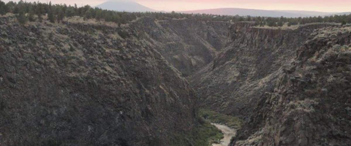 A canyon with a river running through it, surrounded by forested hills.