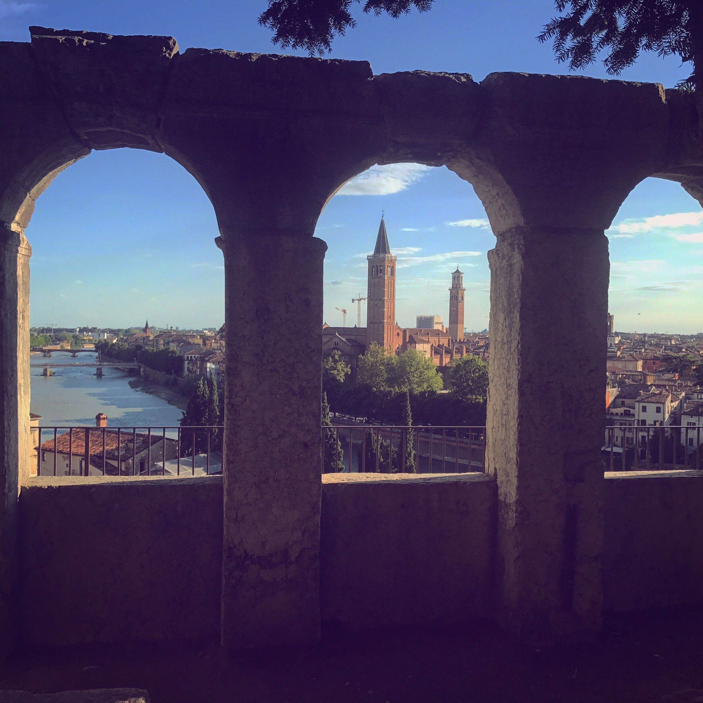 An ancient stone archway overlooking a river and a cityscape with prominent towers.