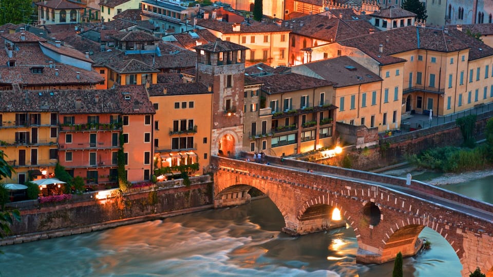 A historic bridge over a river in a European town with colorful buildings.