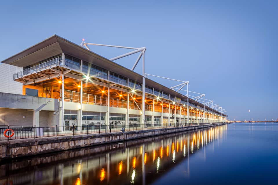 A waterfront building with a modern design, featuring a large overhang and multiple levels.