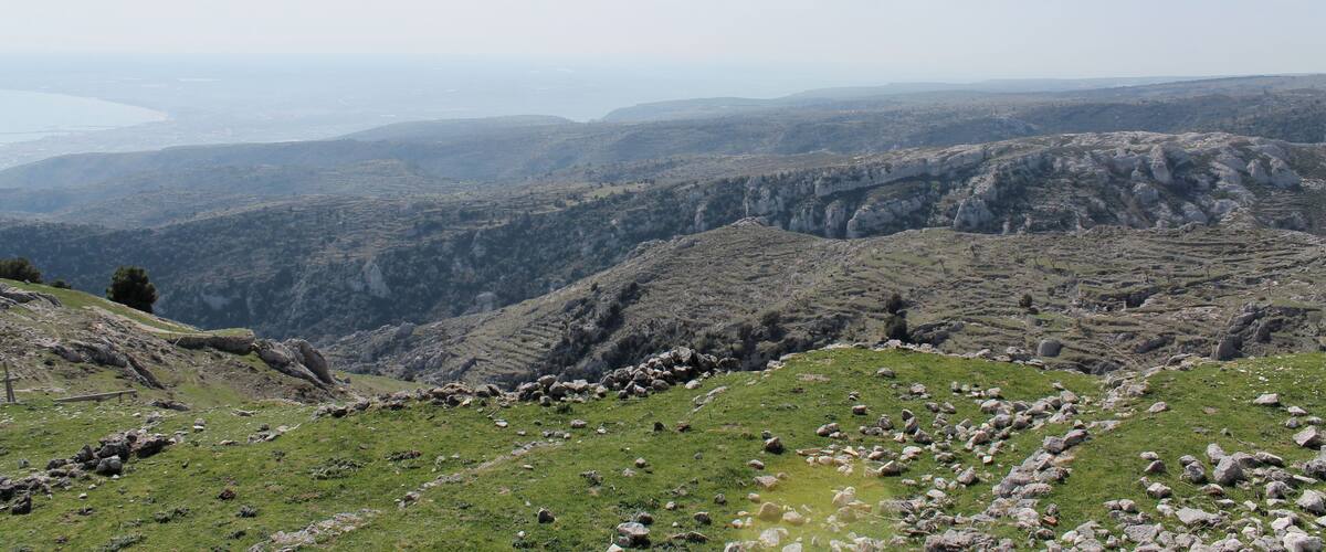 A mountainous landscape with rocky terrain and a distant view of a body of water.