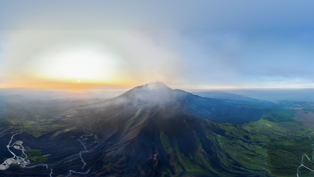Un volcan, un ciel dégagé et un coucher de soleil.