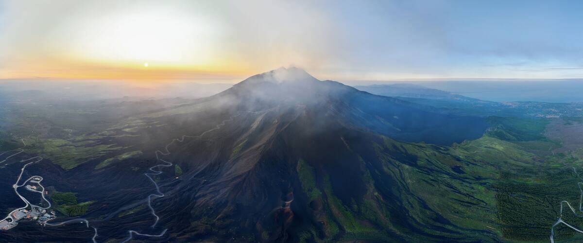A volcano with a clear sky and a sunset.
