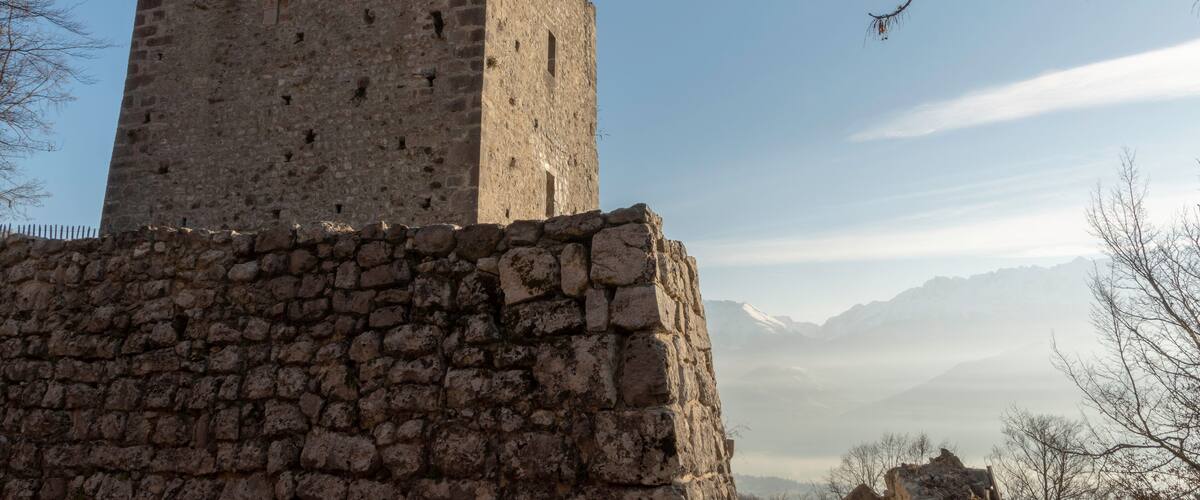 A stone tower with a clear sky and mountains in the background.