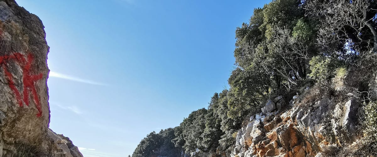 A rocky coastline with clear blue waters and a sandy beach.