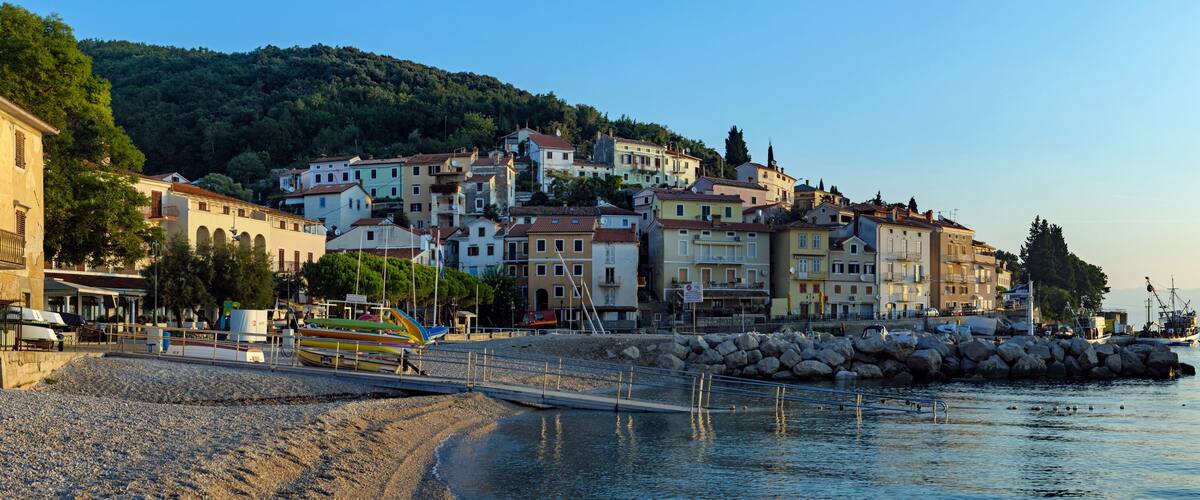 A coastal town with buildings, a rocky beach, and fishing boats.