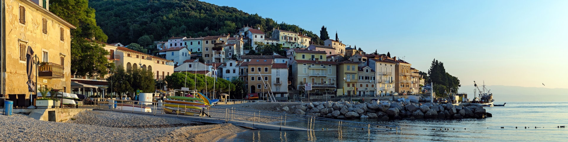 A coastal town with buildings, a rocky beach, and fishing boats.