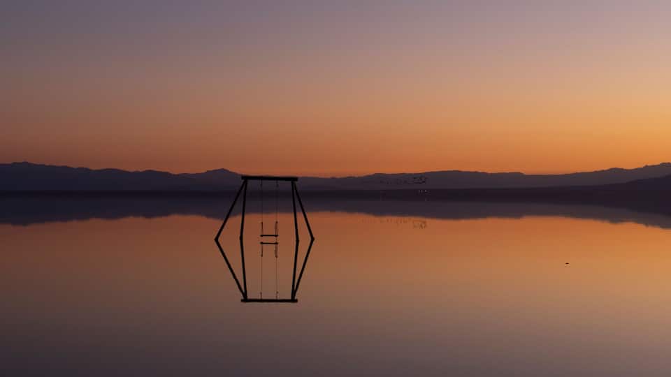 A hexagonal structure in the middle of a calm lake at sunset.