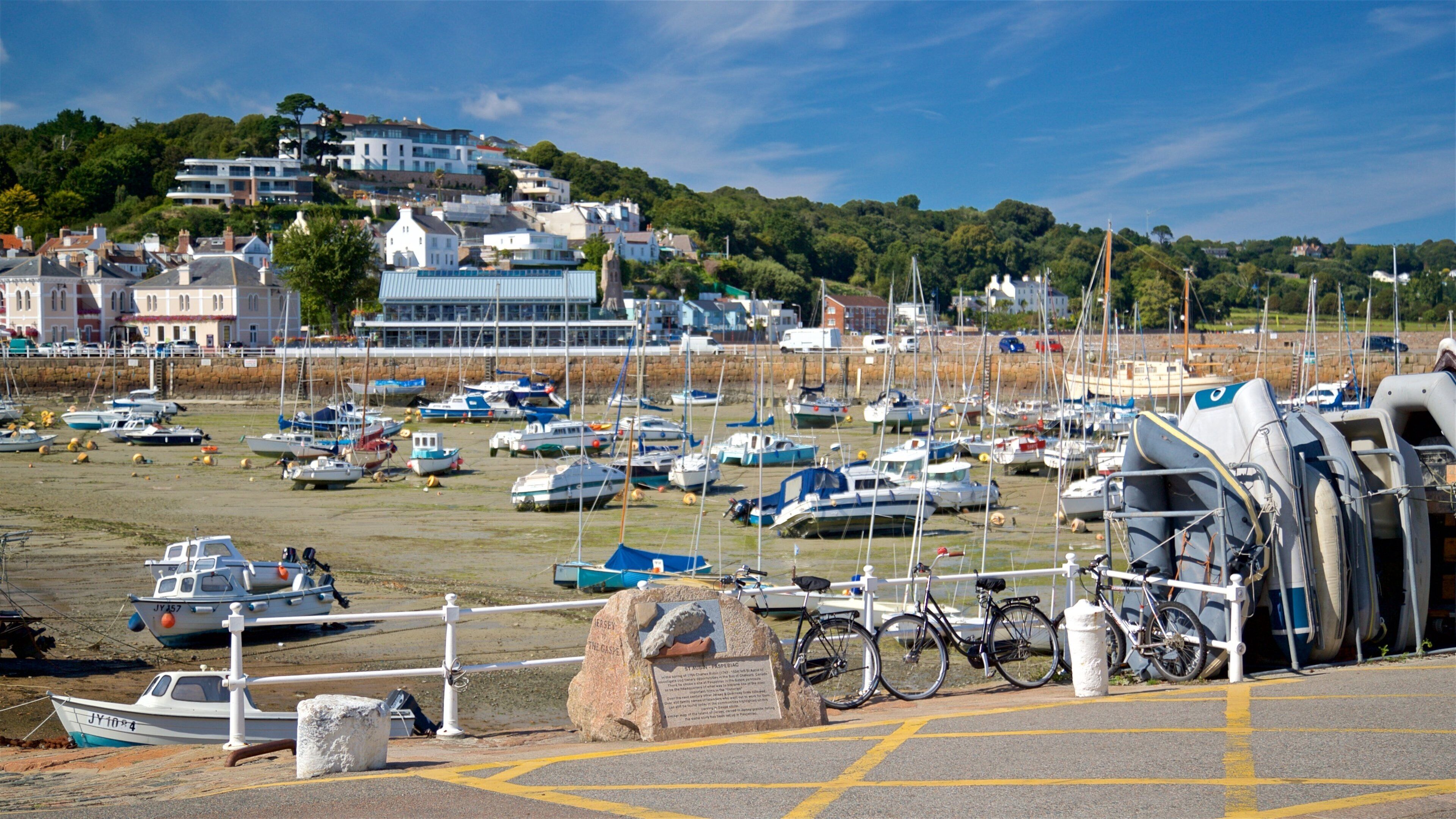 A marina with numerous boats docked, a stone marker, and a bicycle parked near the water's edge.