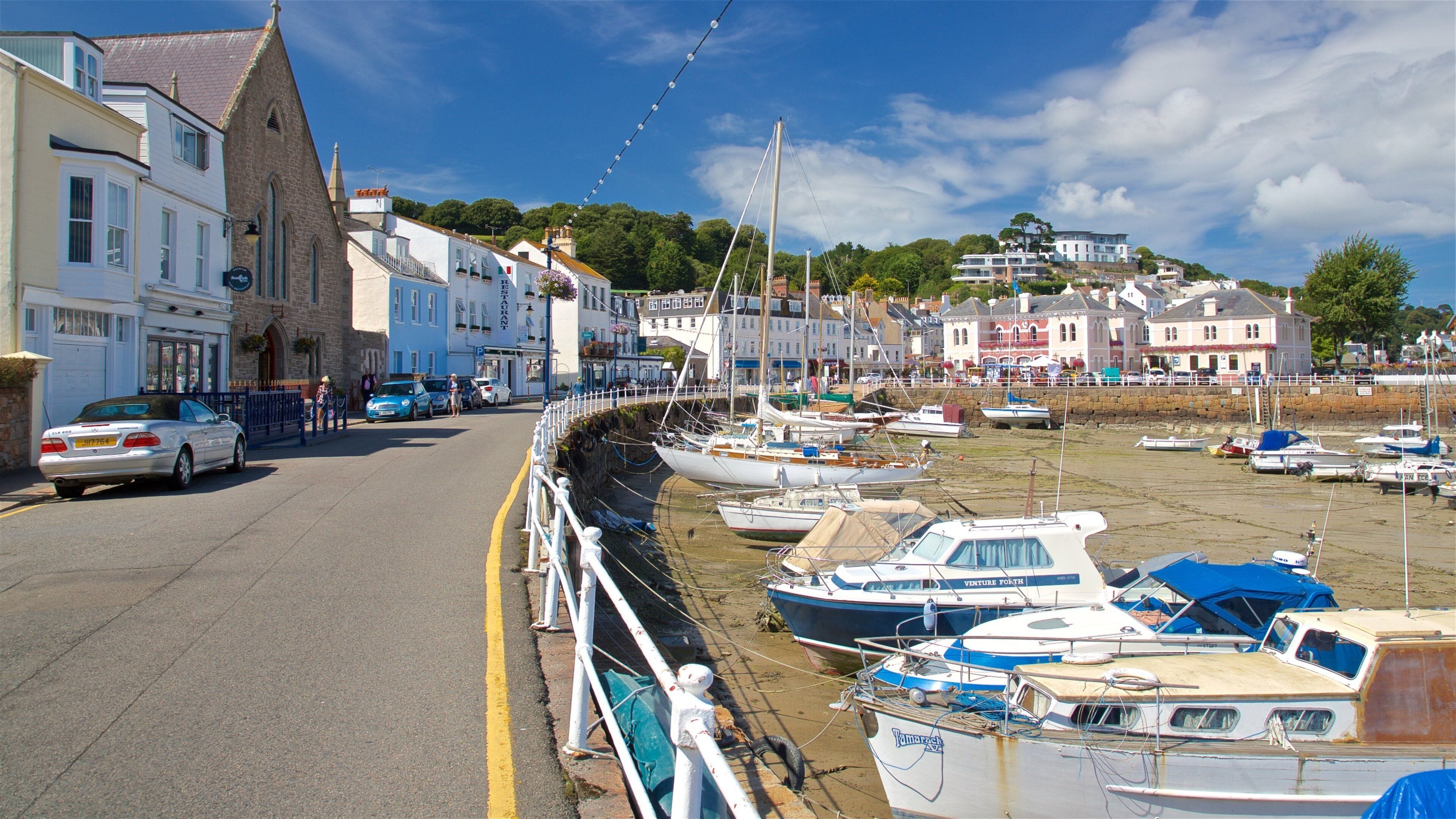 A coastal town with a harbor filled with boats, a church, and buildings along the waterfront.