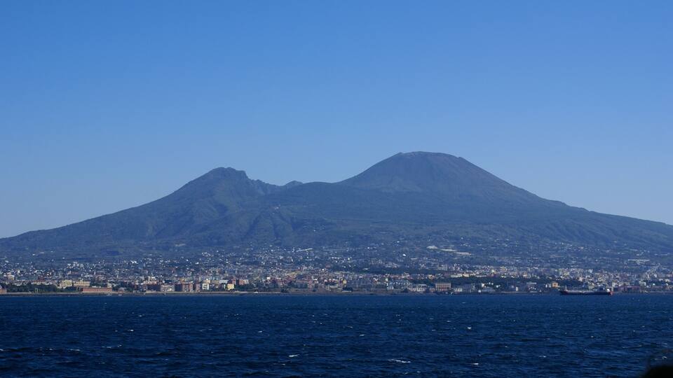 A coastal city with a prominent mountain in the background.