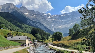 A mountain landscape with a river, a path, and buildings.