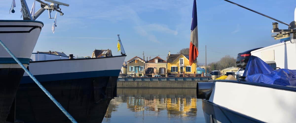 A harbor with boats docked, a yellow building, and a flag.