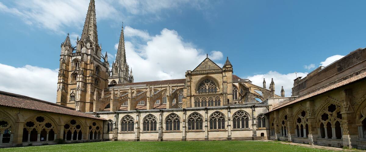 A historic cathedral with intricate Gothic architecture, a large central tower, and a courtyard.