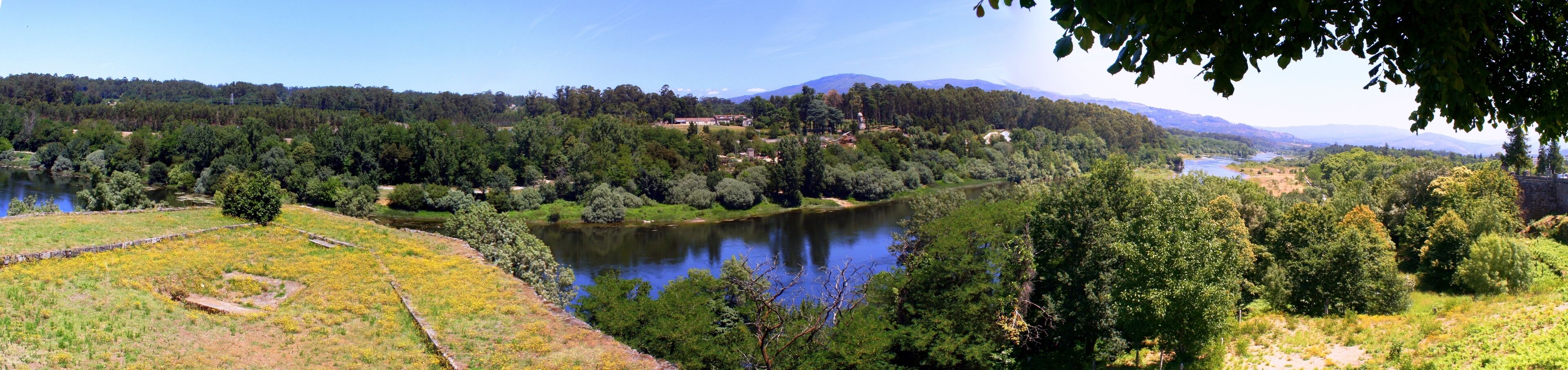 A river winding through a forested valley with a mountain range in the background.