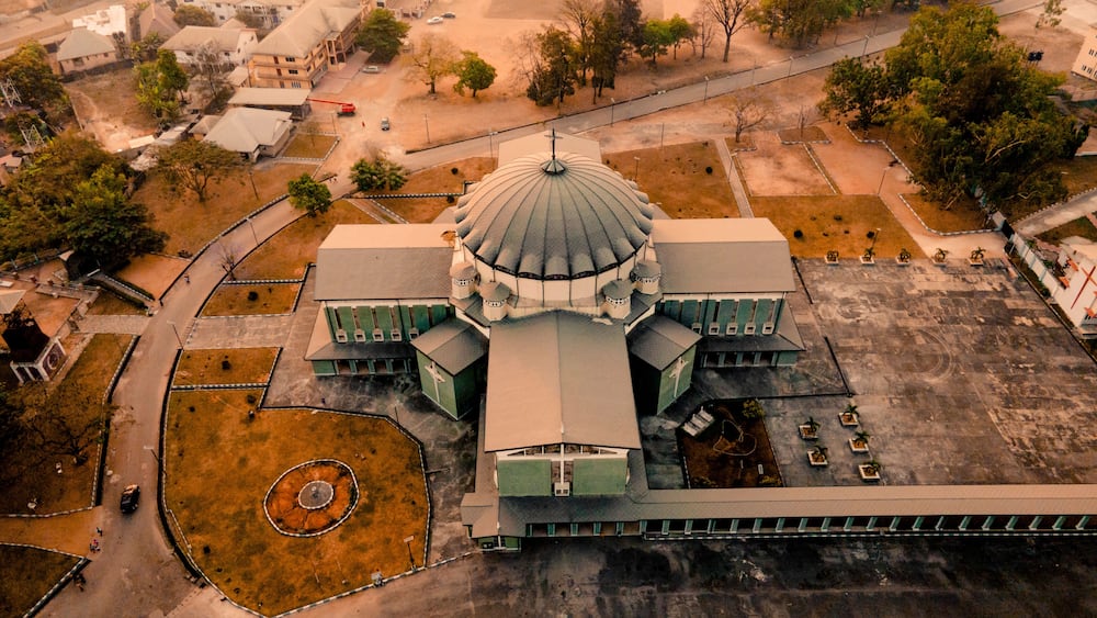 An aerial view of a large, domed building with a central courtyard and surrounding greenery.