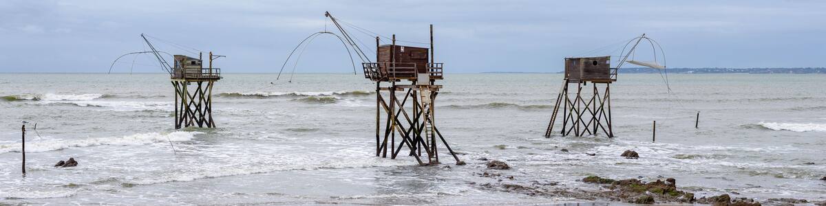 Panoramic view of three typical carrelet fishing huts on a beach in Saint-Michel-Chef-Chef, Loire-Atlantique department, western France.