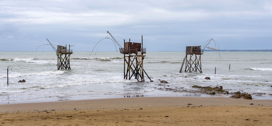 Panoramic view of three typical carrelet fishing huts on a beach in Saint-Michel-Chef-Chef, Loire-Atlantique department, western France.