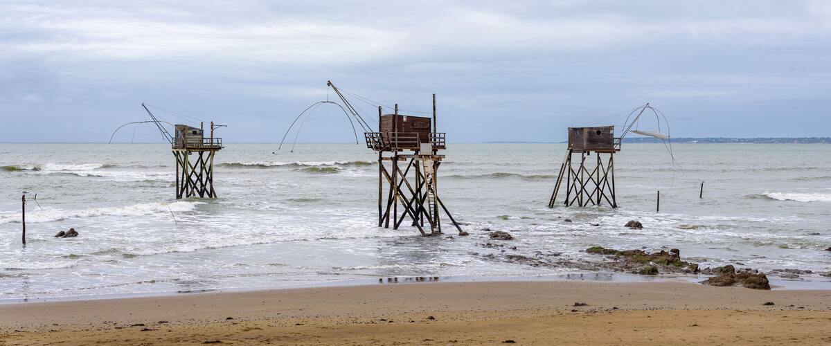 A beach with three wooden fishing platforms extending into the water.