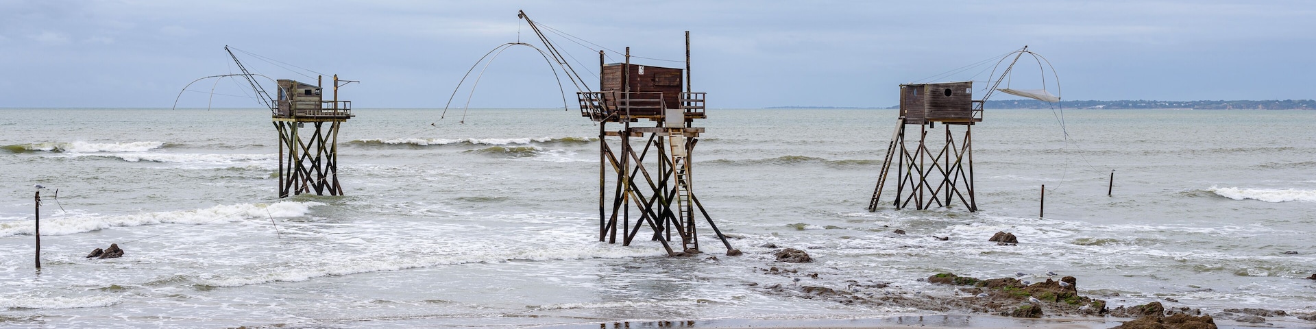A beach with three wooden fishing platforms extending into the water.
