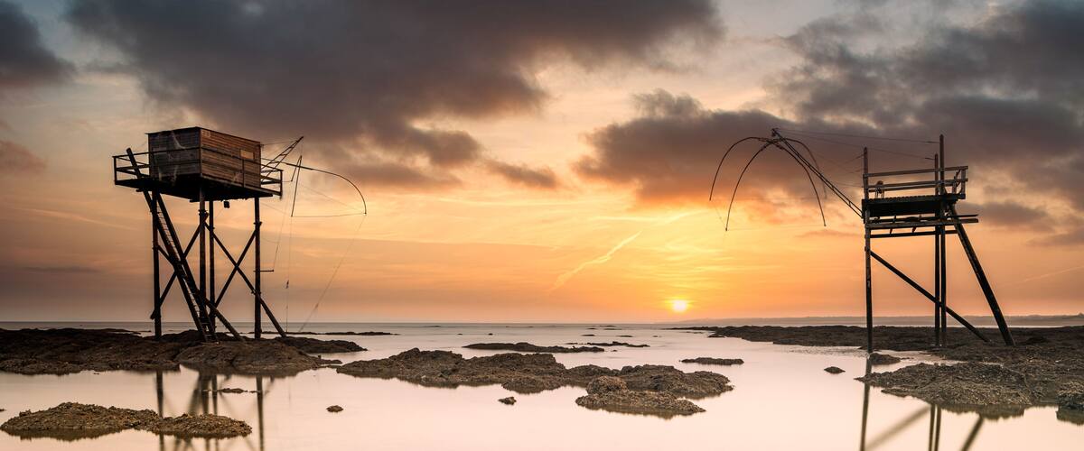 Fishing huts on beach at low tide at sunset, Saint-Michel-Chef-Chef, Loire-Atlantique, France