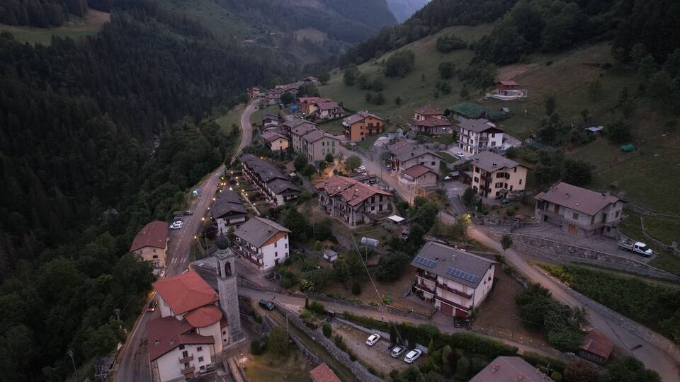 A village nestled in a valley with houses, a church, and a winding road.