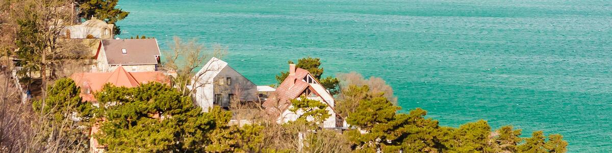 A coastal town with turquoise waters, a church, and rolling hills in the background.
