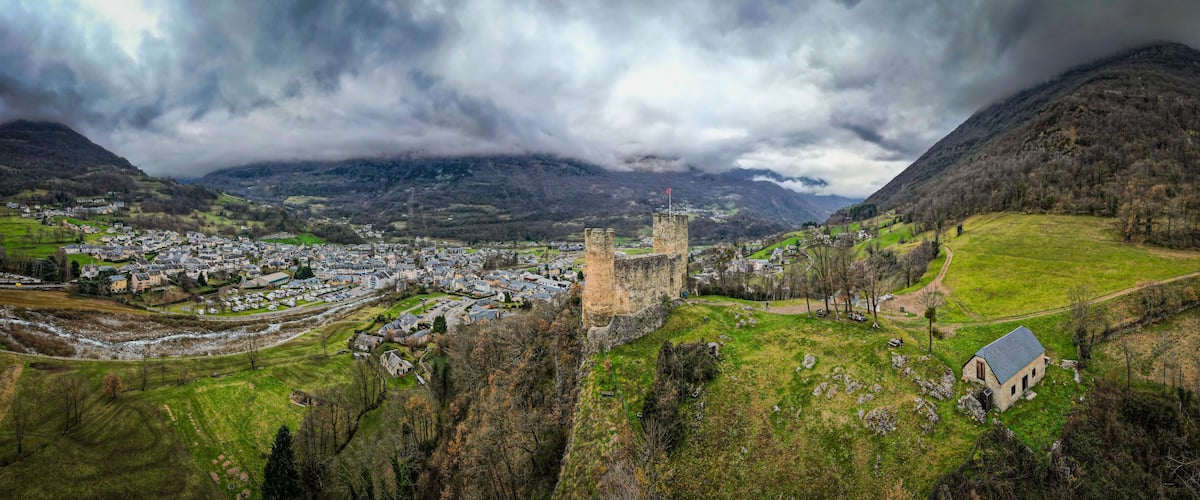 A town with a historic castle, rolling hills, and a river.