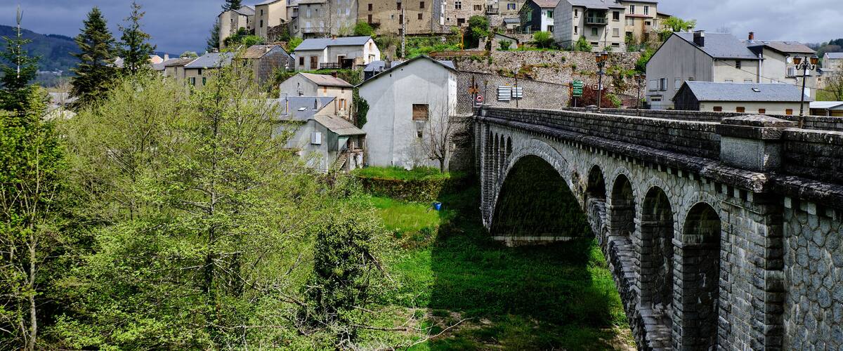 A stone bridge, a hillside of buildings, and a cloudy sky.