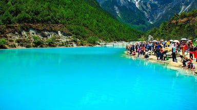 Um lago azul-turquesa rodeado por montanhas verdes e uma multidão de pessoas.