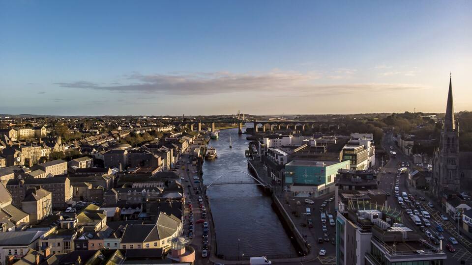 A river running through a city with historic buildings and a bridge in the background.