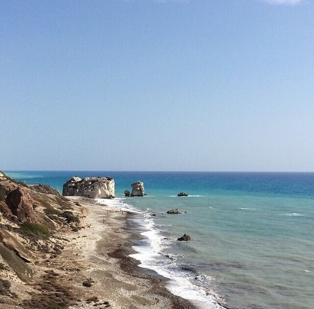 A coastal landscape with rocky cliffs and calm sea.