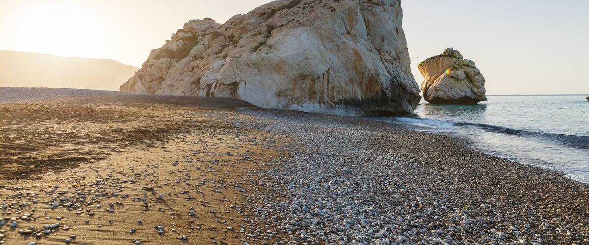A rocky beach with large boulders and a clear sky.
