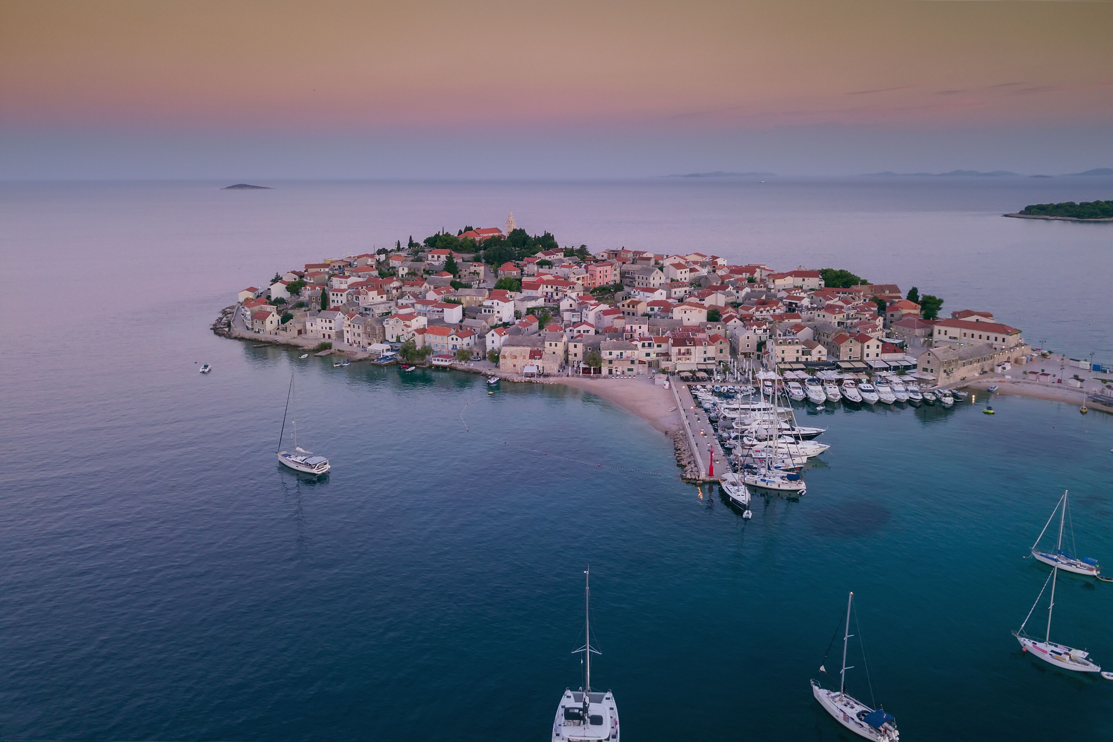 A coastal town with a marina, boats, and a prominent church tower.