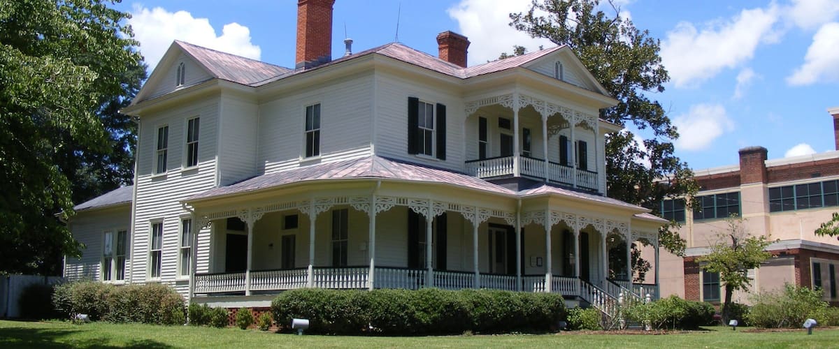 A large, two-story house with a porch and a brick chimney.