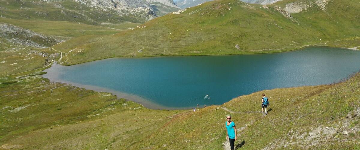 A mountain landscape with a lake and hikers.